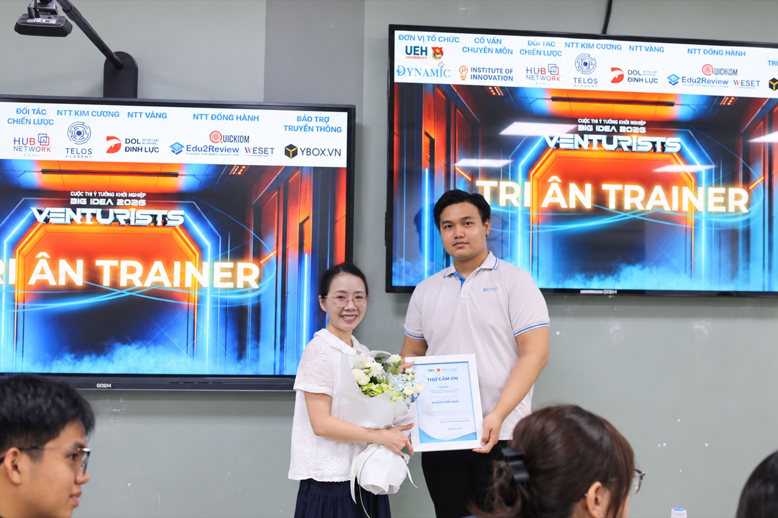 Demi receiving a trainer certificate at the UEH Big Idea 2025 contest